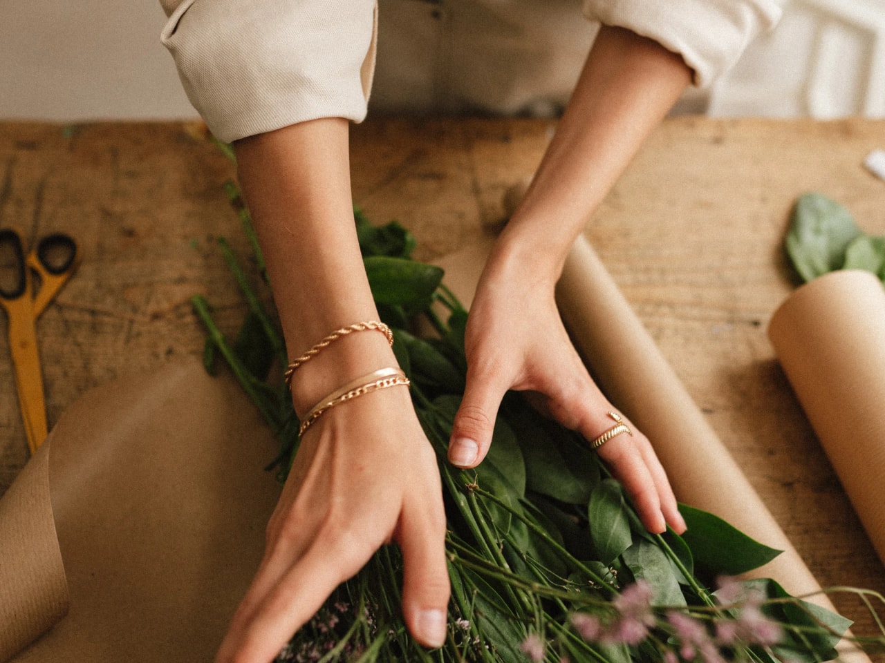 Mains d’une fleuriste Kanel préparant un bouquet sur l’établi de l’atelier