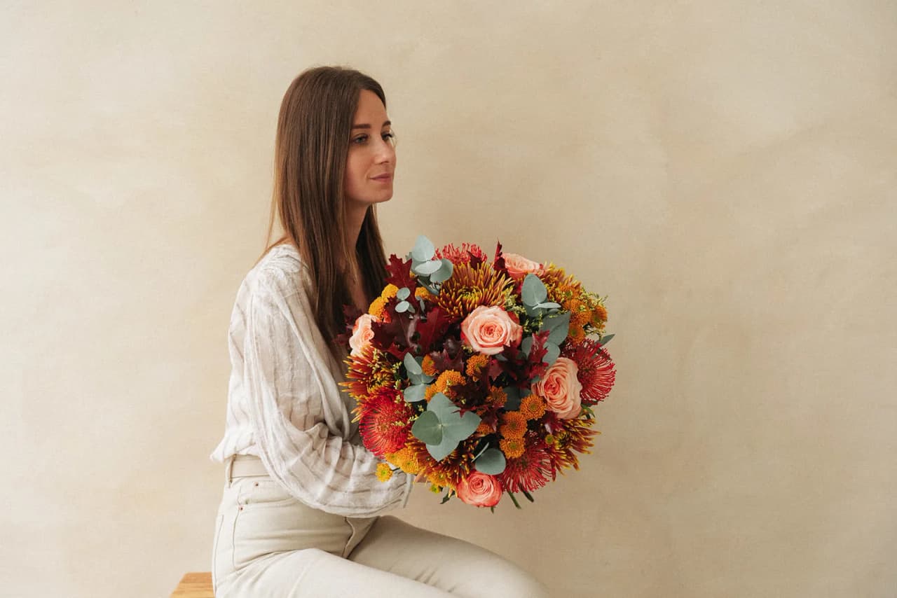 A woman holding an autumn-coloured bouquet