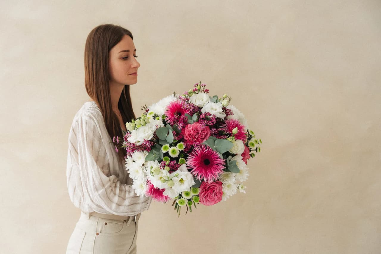 Une femme tenant un bouquet rose et blanc