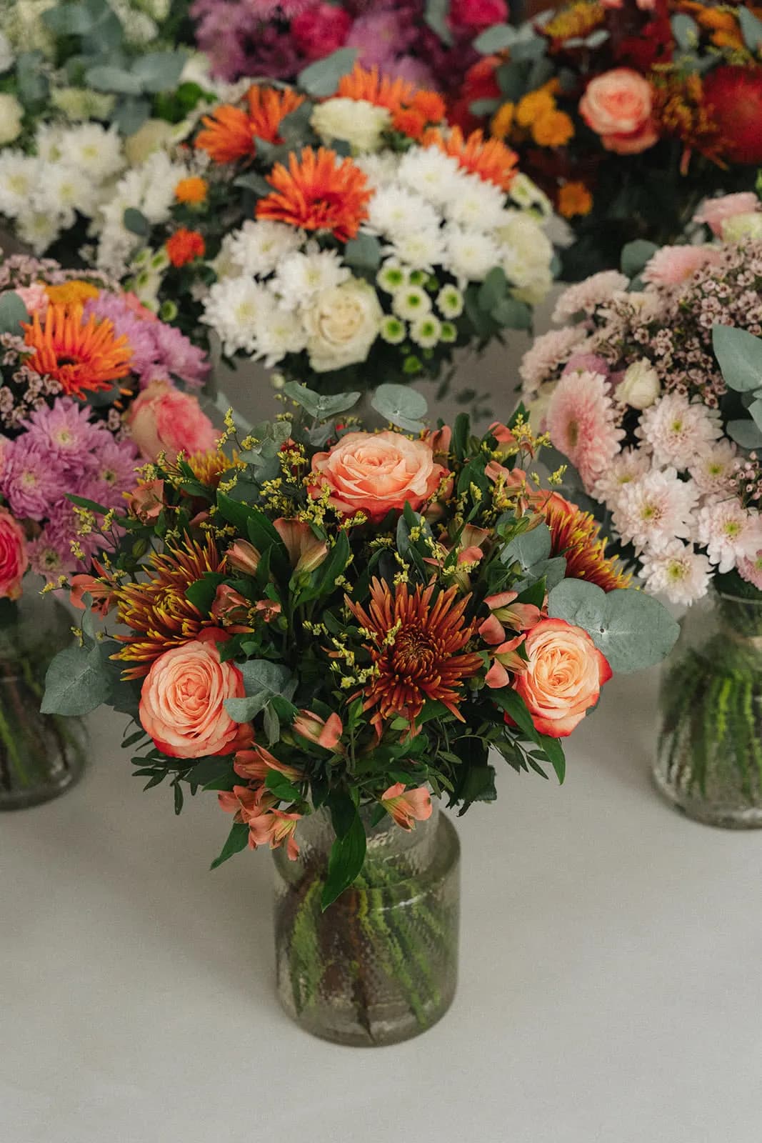 Orange, pink and white bouquets in glass vases