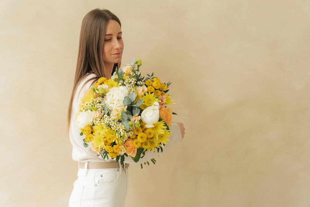 A woman holding a yellow and white bouquet