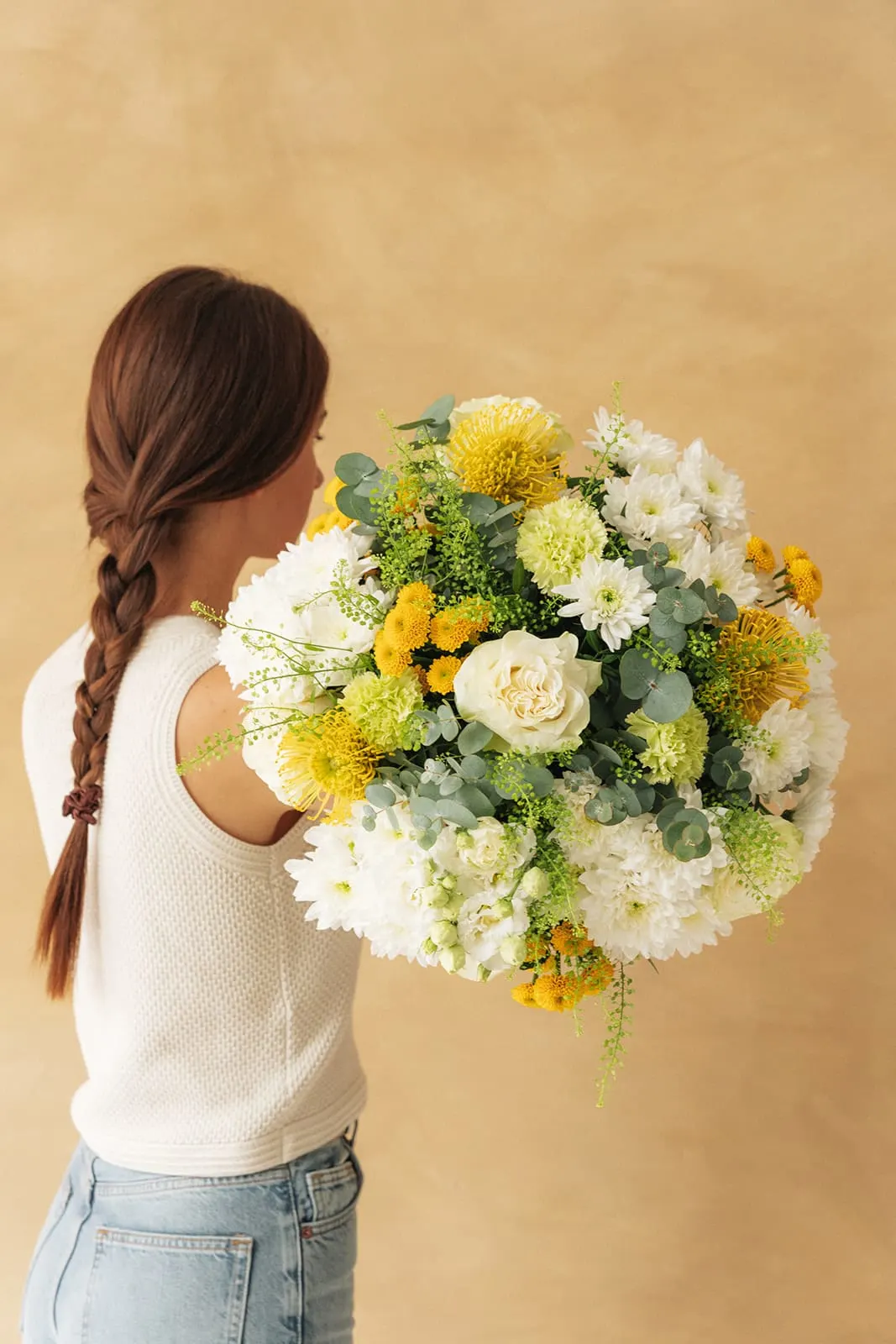 Une femme tenant un bouquet jaune et blanc près du visage