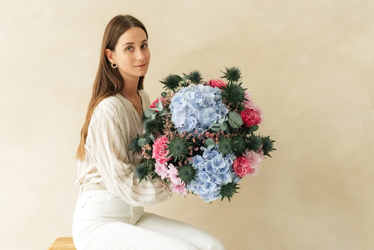 Une femme tenant un bouquet bleu, rose et blanc